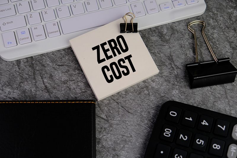 calculator and white note pad with text ZERO COST as a financial and business concept on red background.